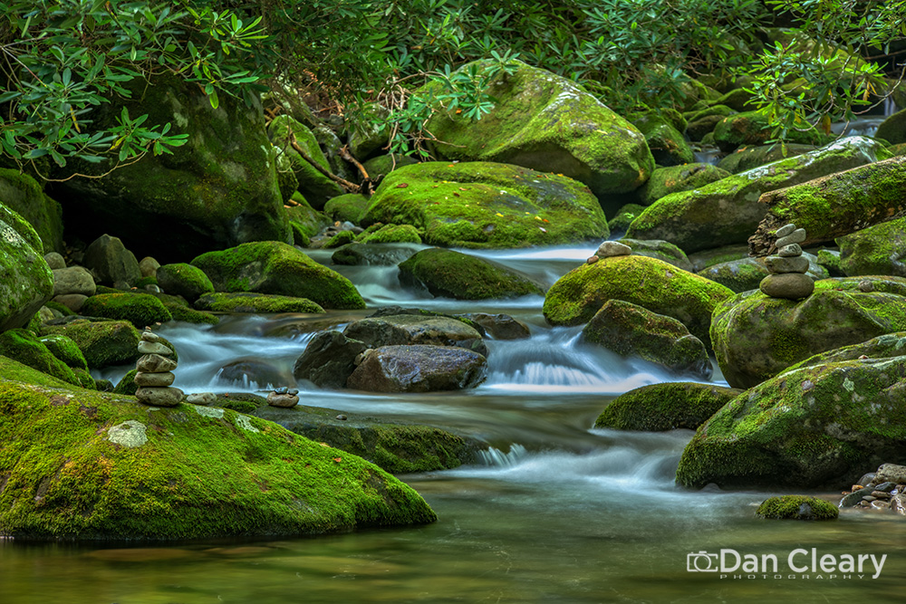 Rock cairns are small piles of stones or rocks, often stacked on top of each other to create a tower-like structure. They are commonly found outdoors on rocky shores, hiking trails, or wilderness areas. They can be used for various purposes, including trail markers, artistic expression, or meditative practice. However, the problem is that people are increasingly building rock cairns to leave their mark or symbol of their presence in a natural setting or for posting on social media. Therefore, when engaging in this activity, it is important to be mindful of the potential negative impacts on the environment, wildlife and other people’s experiences.

Moving rocks and stacking them can disturb the natural habitat of tiny creatures. On the rocky shore, these organisms, such as crabs, molluscs, and algae, depend on their environment’s rocks and other structures for shelter and protection. By moving or stacking rocks, we may inadvertently destroy or disrupt their homes, harming their populations. Similarly, rock stacking can also have adverse terrestrial impacts on insects and moss in wilderness areas.

Building rock stacks can contribute to erosion and destabilization of the shoreline or wilderness area. The rocks on the shore are part of a natural ecosystem and serve an important function in protecting the coastline from erosion and the forces of the ocean. When people move or stack rocks, they can destabilize the shoreline; increase the risk of erosion, and damage ecosystems. Additionally, moving stones and creating cairns can disrupt soil structures and contribute to erosion. This erosion can cause sedimentation in nearby water bodies, negatively impacting aquatic habitats and water quality.
Therefore, it is crucial to be mindful of the potential negative impacts on terrestrial and aquatic environments before engaging in this activity. Let us work together to preserve the natural environment and its inhabitants by refraining from building rock cairns in wilderness areas. Remember, every small action counts towards protecting our planet. #greatsmokymountainsnationalpark #greatsmokymountains #rockcairn #streams #waterfall #nationalparks